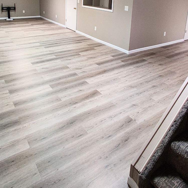 Luxury Vinyl Tile (LVT) flooring installation in a spacious finished basement, featuring a durable and realistic wood finish.